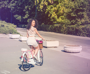 漂亮的女孩在一个粉红色的老式自行车，夏天的生活方式