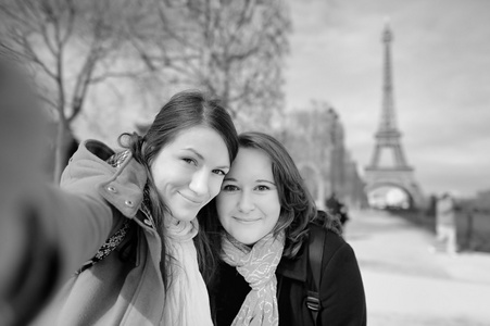两个年轻女子在埃菲尔铁塔附近采取自拍照