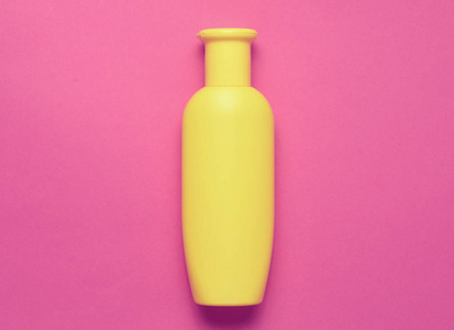 粉红色的背景黄色的洗发水瓶。极简主义趋势。顶部视图。淋浴的产品。文本空间