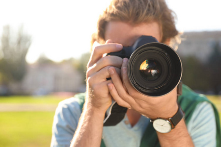 年轻的男性摄影师拍摄照片与专业相机在街上, 特写镜头