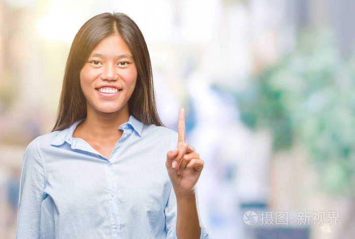 年轻的亚洲商业妇女在孤立的背景显示和指向与手指第一, 而微笑着自信