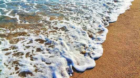 海水与白色泡沫在沿海砂, 自然特写背景