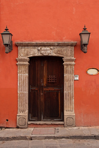 在橙色墙的木质门。墨西哥的典型体系结构