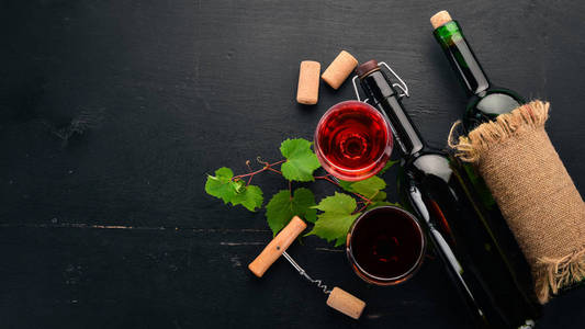 红酒放在瓶子里, 里面有玻璃和葡萄。在黑色的木质背景。文本的可用空间。顶部视图