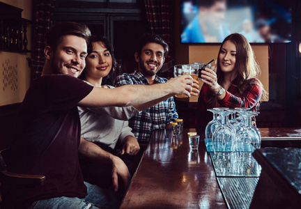 一群快乐多种族的朋友在酒吧或酒吧喝啤酒敬酒