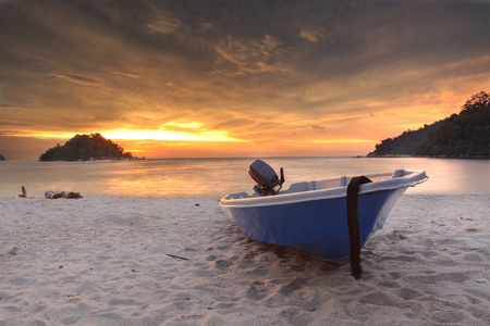 蓝色的渔船在日落时在海滩上