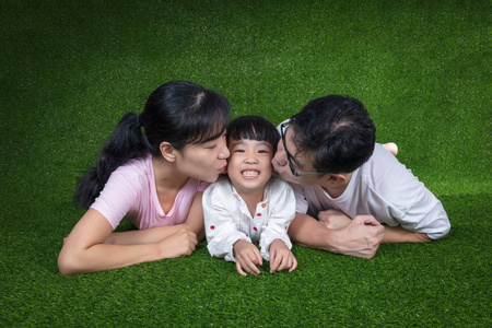 快乐的亚洲中国父母和女儿躺在草地上