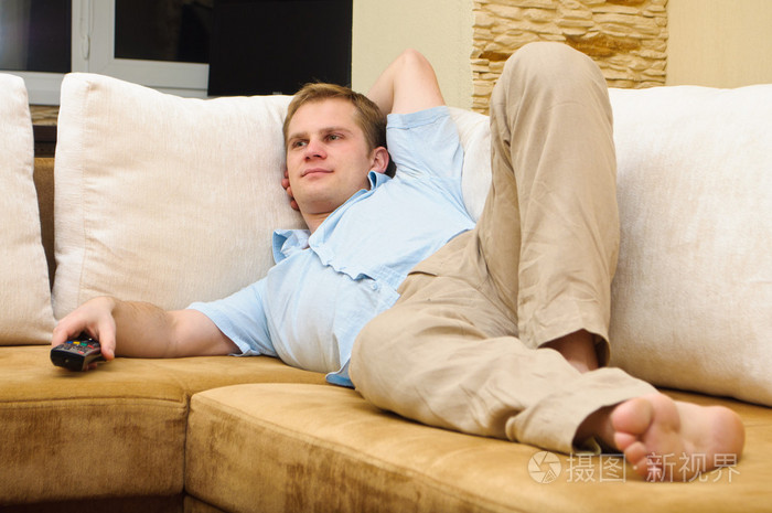 男子躺在沙发在家看电视