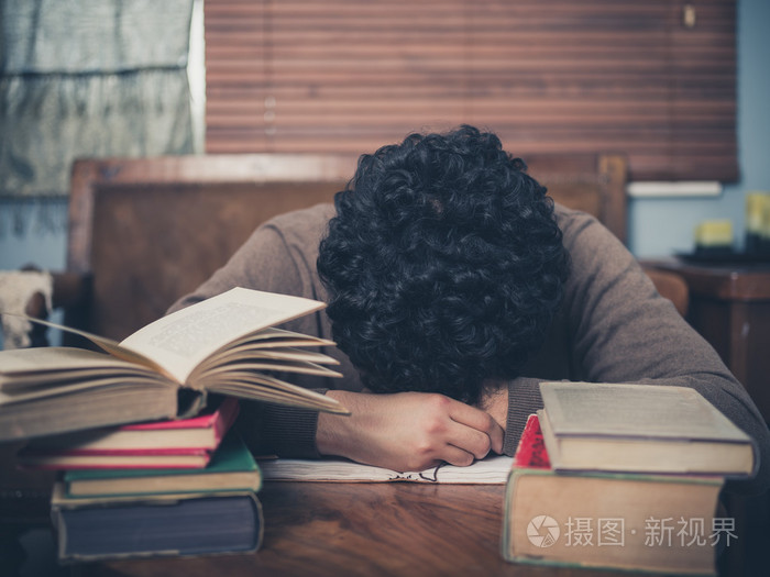疲倦的学生被书籍所包围