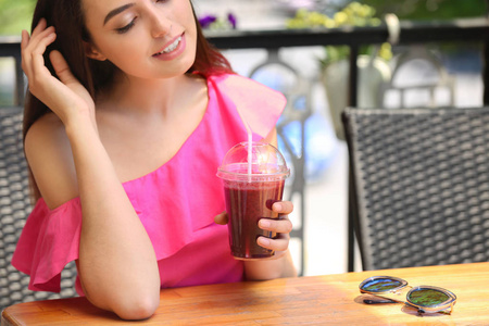 活泼的年轻女性饮用新鲜冰沙在咖啡馆
