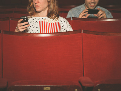 男人和女人在剧院中使用他们的手机