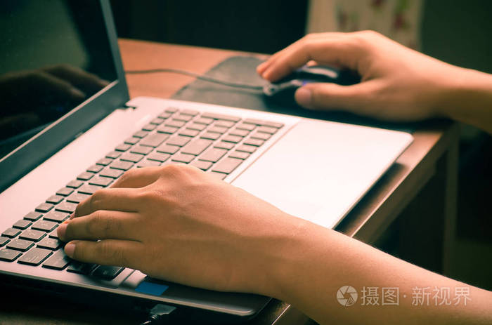 在工作的笔记本电脑键盘上打字的人的手