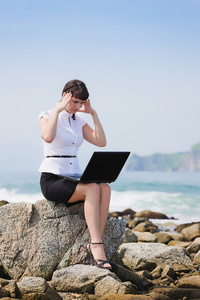 坐在一台笔记本电脑在海滩上的女孩