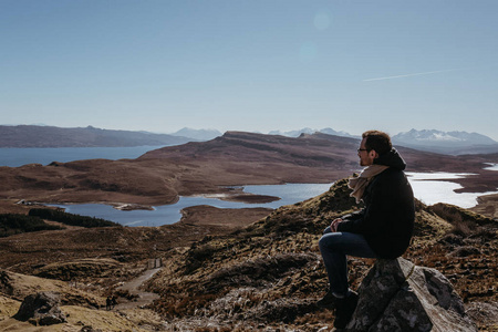 男人在 Storr 的老人上放松, 在斯凯岛上行走, 坐在石头上, 山上和湖上的背景上。