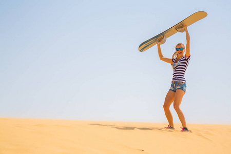 女孩站在沙漠中的一个沙丘上的滑雪板