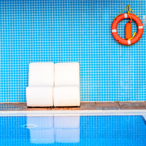 白色椅子上蓝色的背景 橙色的生命浮标附近游泳池
