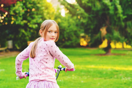 小女孩在夏天公园上自行车肩扛回望