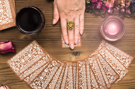 塔罗牌占卜算命的女手和塔罗牌在木桌上。占卜概念照片