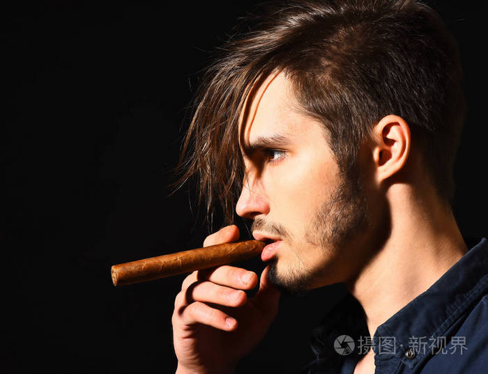 严重的大胡子的男人吸烟雪茄