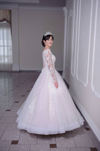 美丽的新娘在一个豪华的白色房间与一个大吊灯的婚纱礼服