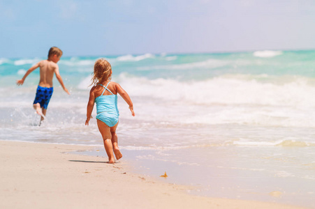 小女孩和男孩跑玩波在海滩上