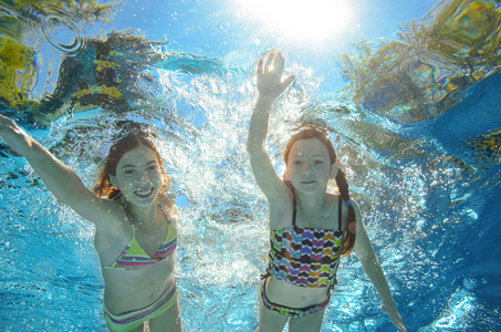 孩子们游泳在游泳池或海洋水下，快乐积极的女孩已经在水里，孩子们运动家庭度假的乐趣
