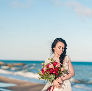 漂亮的新娘在豪华婚纱礼服束在海的那边特写肖像。在海边的婚礼。新娘在婚礼仪式的地方附近海域走来走