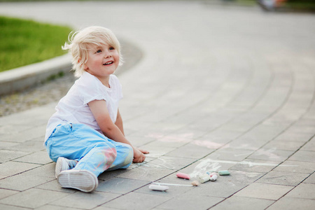 可爱的小男孩在沥青上用彩色粉笔绘制。夏季活动和有创意的游戏，孩子很小