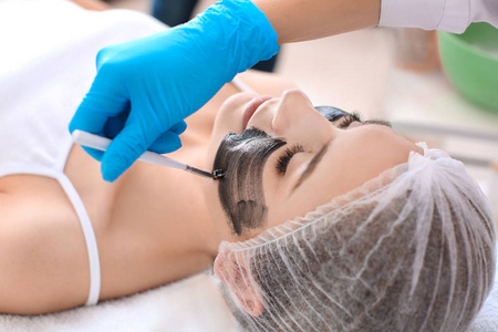 美容师在女人脸上涂抹碳纳米, 特写。剥皮做法