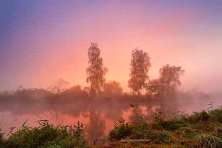 秋天的多彩日出雾静静的河面上。秋雾莫