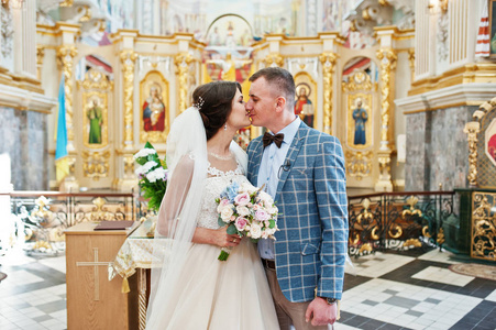 年轻漂亮华丽婚礼情侣接吻在教堂里