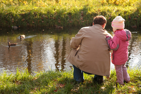 木材在秋季的孙女与祖父看看鸭子在水中图片