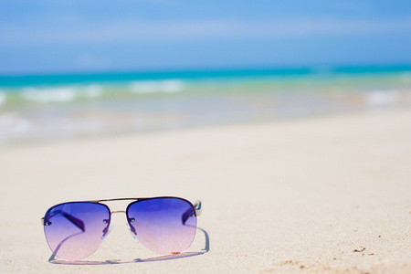 躺在热带沙滩上的蓝色太阳镜。一方