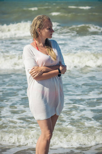 一个美丽的女人站在海边与抱在胸前用手
