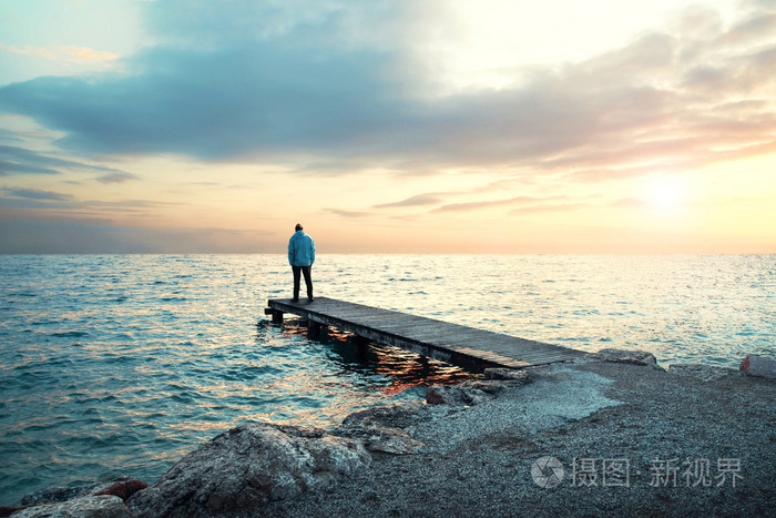 孤独的人站在木板路看海