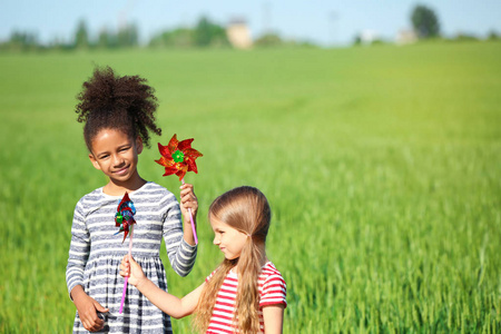 快乐的小女孩，与玩具风车在绿色的田野