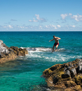 健康的年轻人跳入海洋在鲁玛海海滩考艾岛