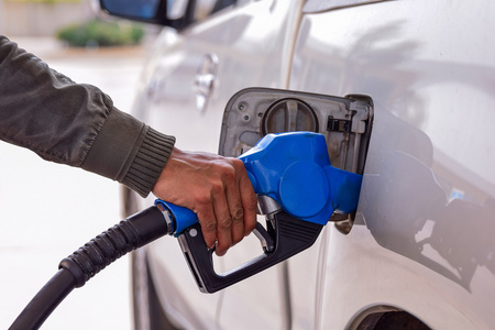 男子举行燃油喷嘴在汽车加油站中添加燃料