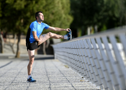 运动员男子伸展腿小腿肌肉运行倚栏杆市城市公园锻炼之前热身