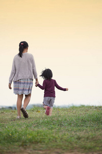 年轻妹妹晚上在绿草上散步