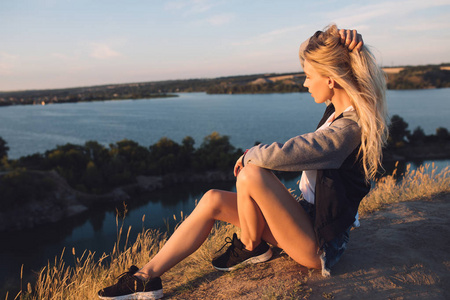 徒步旅行者的女孩。独自旅行。年轻女子与冒险的旅行。她坐在性质上和期待采石场