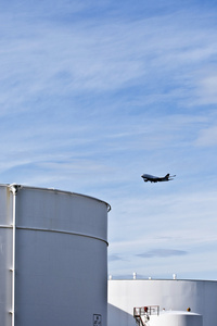 白色的坦克在罐区与蓝蓝的天空和接近飞机