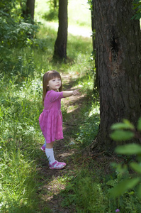 可爱的小女孩，在粉红色的连衣裙在森林里。森林女神。阳光灿烂的日子