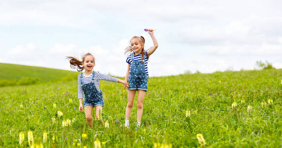 快乐的孩子们对双胞胎姐妹又跳又笑在夏天