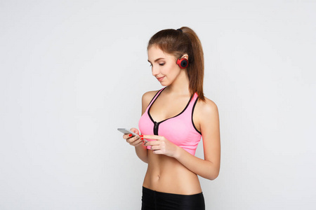 耳机的健身女孩选择手机上的音乐