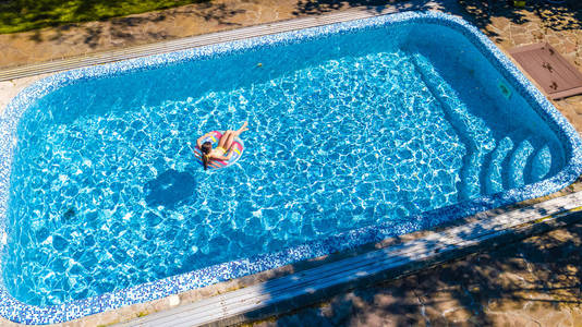 女孩在游泳池从上面鸟瞰孩子游泳上充气环甜甜圈和家庭度假已在水中嬉戏