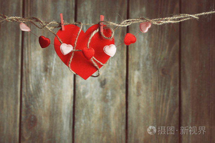 明亮的心挂在绳子上木制背景