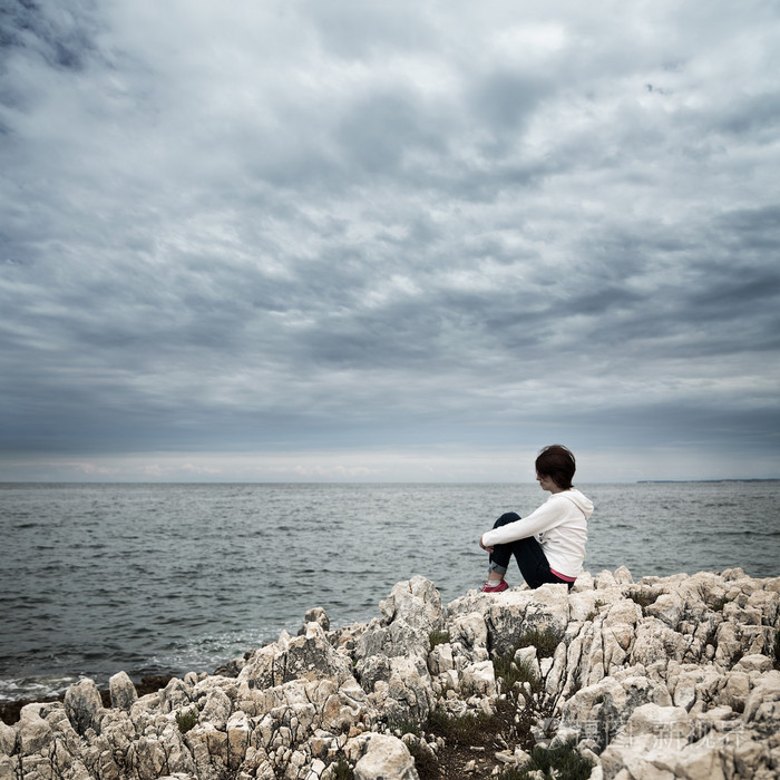 孤独的女子坐在波涛汹涌的海面