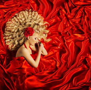 红色真丝织物上的头发美艺术，女人美丽的卷发发型，金发时尚模型睡眠