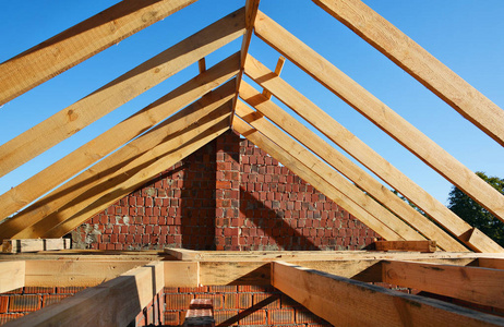 木制的屋面工程施工。未完成的房屋建筑。安装的木梁施工在房子的屋顶桁架系统